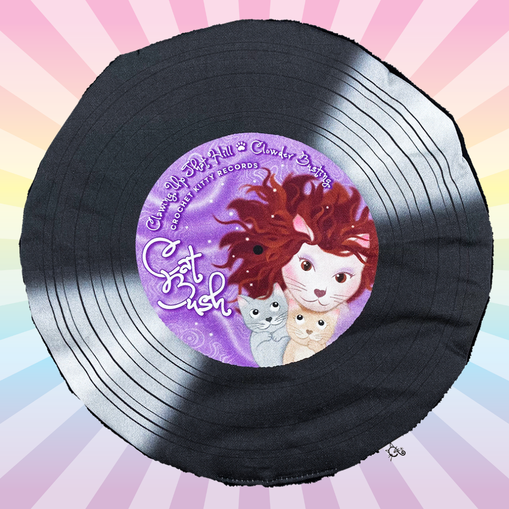 Black Cat Bush catnip record mat with a purple cat illustration label on a pastel rainbow sunburst background.