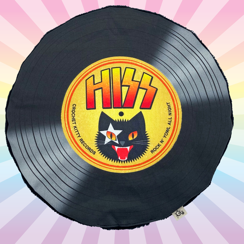 Hiss catnip record mat with a yellow rock-cat label on a pastel rainbow sunburst background.